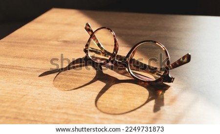 Glasses on wooden table. Sunshine reflecting on vintage glasses on the table. Wisdom concept. Copy space for text Royalty-Free Stock Photo #2249731873