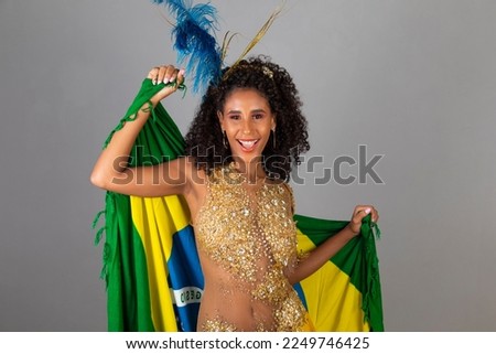 Brazilian afro woman posing in samba costume on grey background with the flag of Brazil
