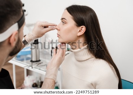 Rhinoplasty is reshaping nose surgery for change appearance of the nose and improve breathing. ENT doctor is touching nose and consulting girl patient in medical clinic before septoplasty surgery Royalty-Free Stock Photo #2249751289
