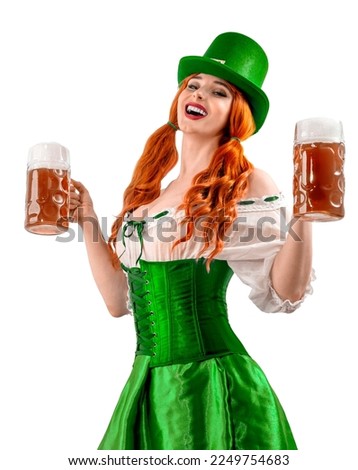 Happy Irish girl holding big mugs with beer or ale. Young red-haired woman аs green Leprechaun elf character for advertising. St. Patrick's Day party. Ireland National Independence Day March 17th.