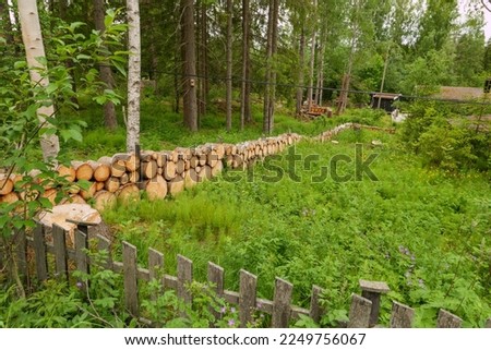 Wooden fence made of sawed-off tree trunks at an overgrown property at the edge of the forest. Seen on the pilgrimage route Olavsweg just before Hamar in Norway, Innlandet province.