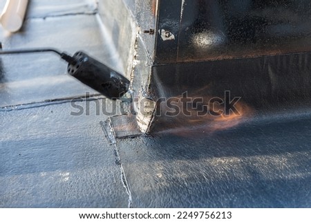 Craftsman scraps on construction site for sealing on the roof with gas scavengers - close-up Royalty-Free Stock Photo #2249756213