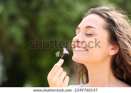 Happy candid woman smelling little flower in a park Royalty-Free Stock Photo #2249760147