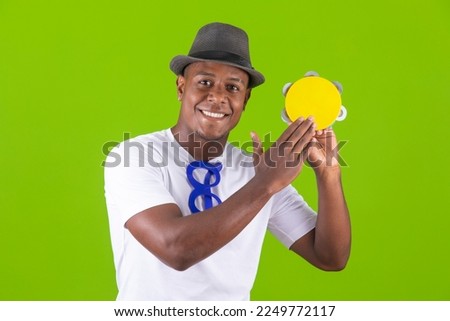 handsome black man, happy playing a carnival tambourine
