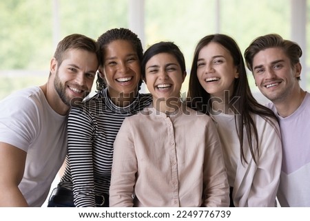 Multiethnic team of joyful happy students, interns, friends posing close together, looking at camera with toothy smiles, laughing, enjoying meeting, social communication, group success