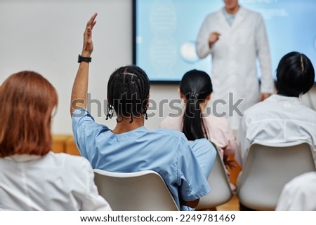 Back view at young black doctor raising hand in audience at medical seminar, copy space Royalty-Free Stock Photo #2249781469
