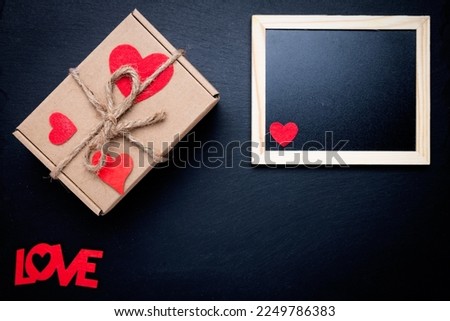 Photo frame and box with a gift on a black background. Space for text. Word LOVE. Congratulations on Valentine's Day.