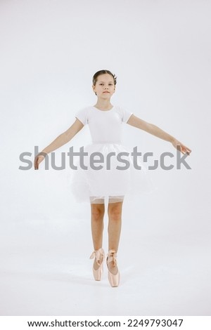 Girl ballet dancer in white dress against white background
