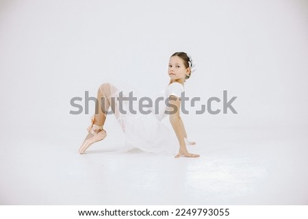 Girl ballet dancer in white dress against white background