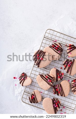 Heart shaped strawberry cut out cookies with dark chocolate glaze and sprinkles for Valentines day, copy space