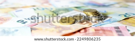 Stack of coins on euro banknotes as wide panoramic format, website header concept for business, finance or inflation, copy space, selected focus, narrow depth of field Royalty-Free Stock Photo #2249806235