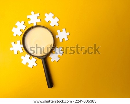 Magnifying glass searching missing puzzle on yellow background