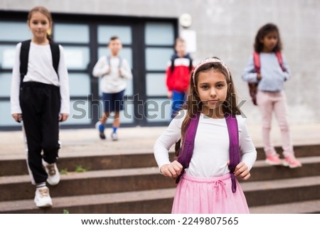 Portrait of smiling schoolgirl standing on the street, kids on background