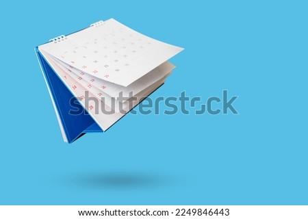 White paper desk calendar flipping page isolated on blue background
