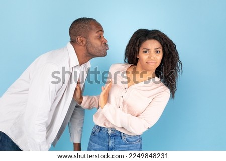 Stay away from me. African american couple, middle aged man in love reaching and trying to kiss confused young woman, lady rejecting him and showing stop sign gesture, blue studio background Royalty-Free Stock Photo #2249848231