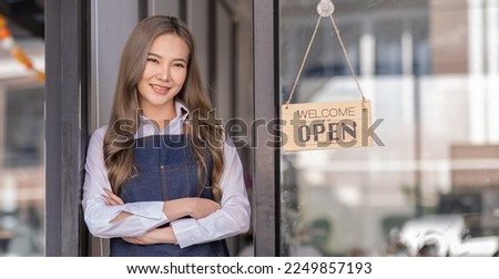 Portrait of Asian attractive small business owner standing in her shop entrance open sign, Portrait of asian tan woman barista cafe owner. SME entrepreneur seller business concept