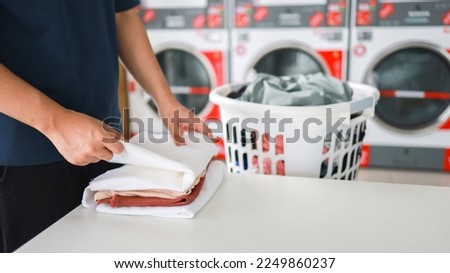 Man doing launder holding basket with dirty laundry of the washing machine in the public store. laundry clothes  Royalty-Free Stock Photo #2249860237