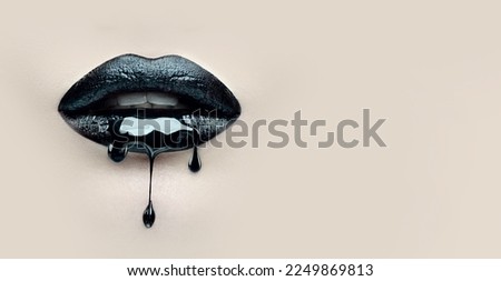 Black Paint dripping from the lips, dark liquid drops on beautiful model girl's mouth on beige background. Halloween party make-up, gothic style. Beauty makeup close up. Wide screen art backdrop. 