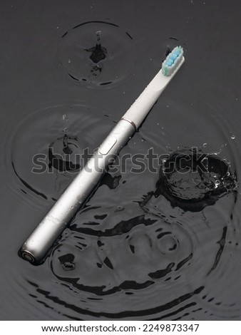 Modern sonic electric toothbrushes. Made from gray metal. Professional oral care and healthy teeth. Minimalistic design. They lie in the water. Black background.