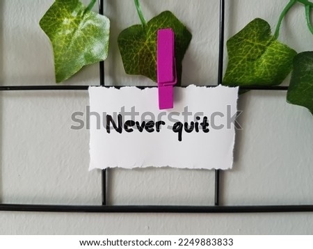 Never quit inscription on wall background.