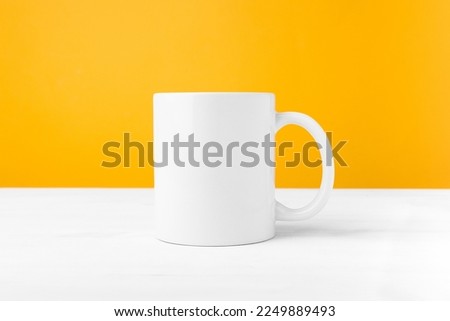 White ceramic mug with blank copy space front view. Cup mockup for advertising and logo on a wooden table.