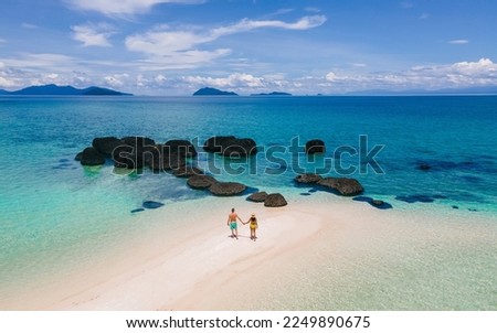 couple walking at the beach of Koh Kham Trat Thailand, aerial view of the tropical island near Koh Mak Thailand. white sandy beach with palm trees and big black boulder stones in the ocean Royalty-Free Stock Photo #2249890675
