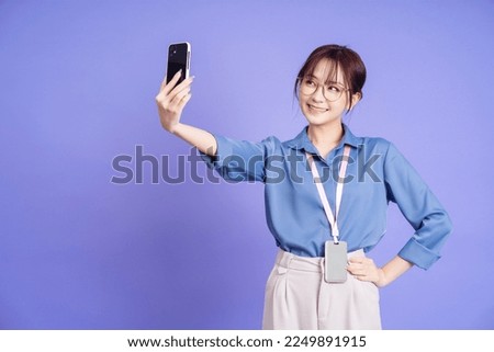 Photo of young Asian businesswoman holding smartphone on background