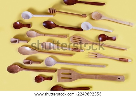 Wooden kitchen utensils, tools and equipment on yellow background. Home kitchen tools and accessories for cooking.