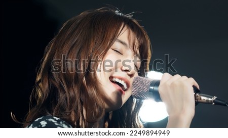 A woman singing in the spotlight. Live. concert. Karaoke. Royalty-Free Stock Photo #2249894949