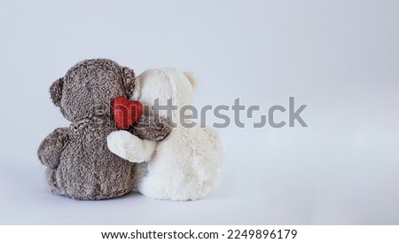 Two teddy bears hugging. One of them is holding a glitter red heart. Valentine's Day background, love celebration concept image with copy space
