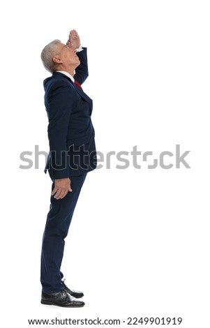 Full body picture and side view of an old businessman protecting his eyes from sunlight to see better what's up above him
