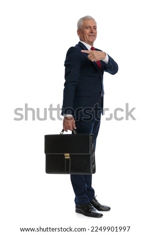 Full body picture and side view of an old business man pointing behind him and holding a black Briefcase