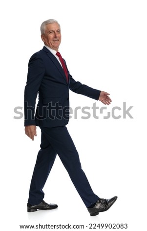 Full body picture of an old businessman walking to the side with his hands hanging loosely