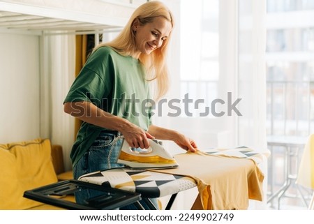 Middle-aged woman housewife ironing clothes at home. Royalty-Free Stock Photo #2249902749