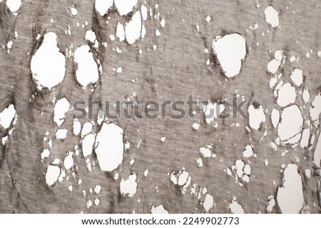 old dirty ragged shirt texture, grunge damaged ripped texture cloth for background. Torn gray white fabric with many holes Royalty-Free Stock Photo #2249902773