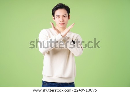 Portrait of young Asian man posing on green background Royalty-Free Stock Photo #2249913095
