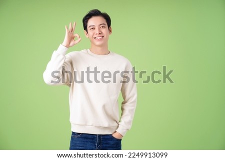 Portrait of young Asian man posing on green background Royalty-Free Stock Photo #2249913099