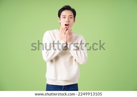 Portrait of young Asian man posing on green background Royalty-Free Stock Photo #2249913105