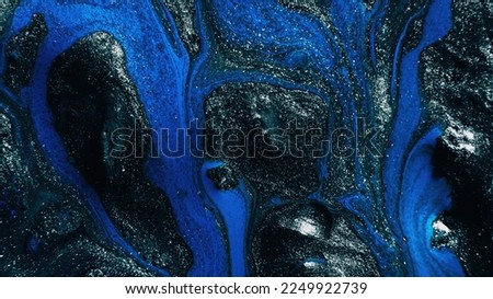 Fluid art. Glitter paint. Marble texture. Defocused shimmering silver gray blue black color ink blend wave on dark abstract background.
