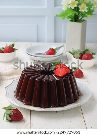 chocolate pudding on white plate topping strawberry slices. decorated strawberry fruits, white saucer and white vas. selected focus. agar agar coklat or pudding coklat Royalty-Free Stock Photo #2249929061