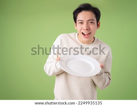 Image of young Asian man holding plate on background Royalty-Free Stock Photo #2249935135