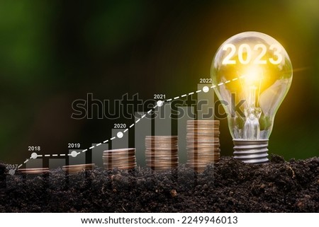 Stack of coins in the soil with growth compared to 2017-2023 and bulbs for innovations and ideas for the new year. investment growth Evolve to Success in 2023 Royalty-Free Stock Photo #2249946013