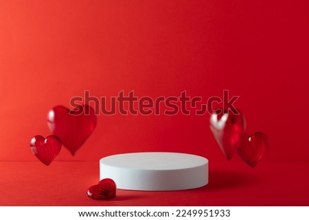 White podium with red hearts on red background to show cosmetic products. Minimal romantic backdrop with stand for branding and presentation on Valentine's Day