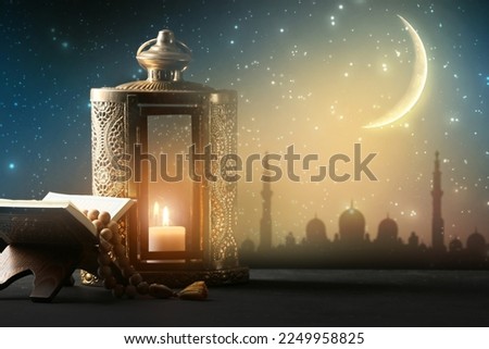 Muslim lantern with Quran and tasbih on table at night Royalty-Free Stock Photo #2249958825