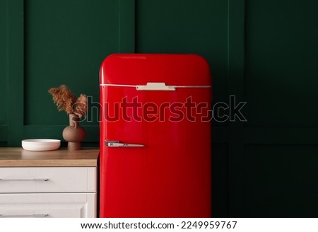 Red fridge, vase with pampas grass and bowls on counter near green wall
