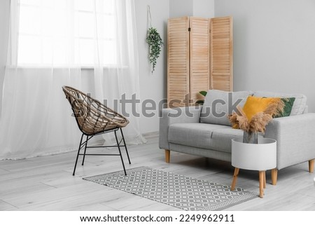 Interior of living room with sofa and wicker chair grass near window