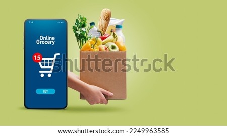 Hands holding a box full of fresh groceries and online grocery shopping app on smartphone Royalty-Free Stock Photo #2249963585