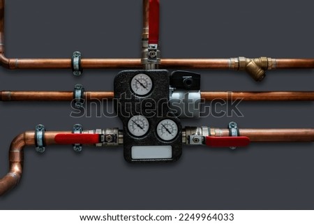 Copper pipes and thermoregulator with valves on a grey wall. Close up.. Royalty-Free Stock Photo #2249964033