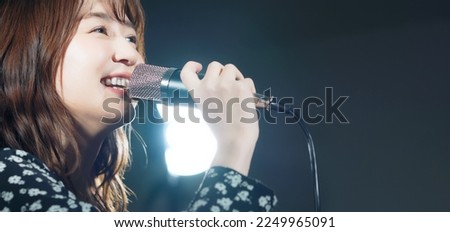 A woman singing in the spotlight. Live. concert. Karaoke. Royalty-Free Stock Photo #2249965091