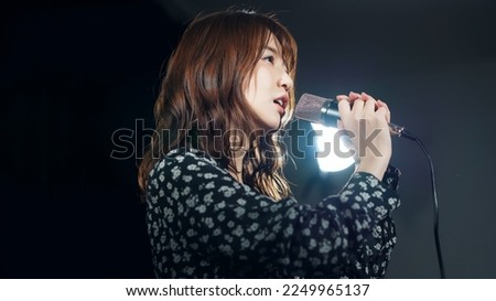 A woman singing in the spotlight. Live. concert. Karaoke. Royalty-Free Stock Photo #2249965137